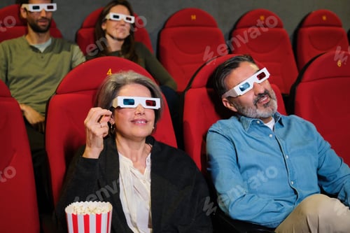 Preview: Group of people watching 3d movie in cinema theater enjoying popcorn