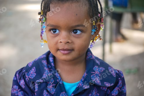 Preview: Portrait of a cute little girl of mixed or black race with braided hair and big bright eyes