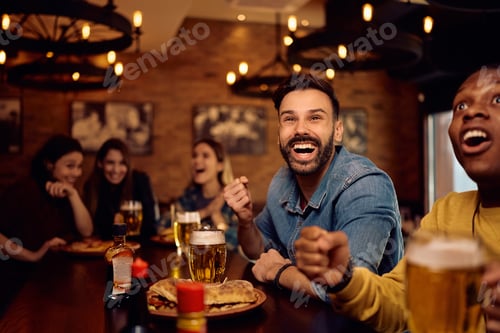 Preview: Cheerful man watching sports game with his friends in a pub.