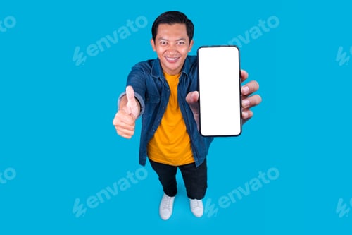 Preview: Top View Of Asian Young Man Showing Blank Screen On Smartphone While Giving Thumb Up