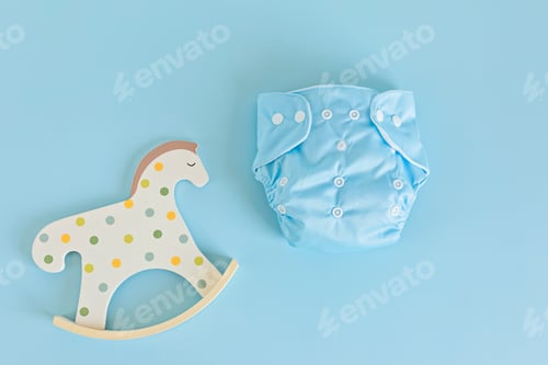 Preview: Flat lay with reusable cloth baby diaper and toy rocking horse