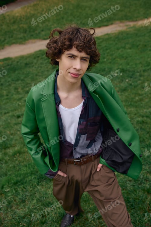 Preview: Young student enjoys a peaceful walk outdoors in a vibrant green jacket on a sunny day