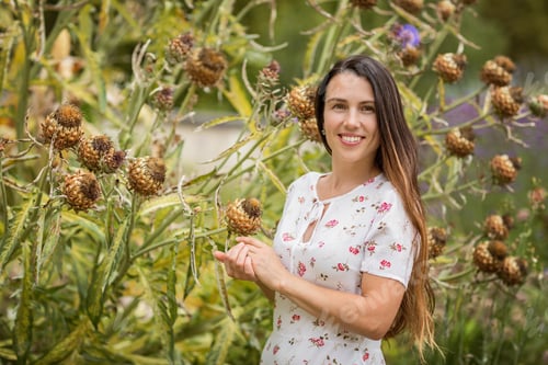 Preview: Young beautiful woman standing near big burdock plant in old overgrown park