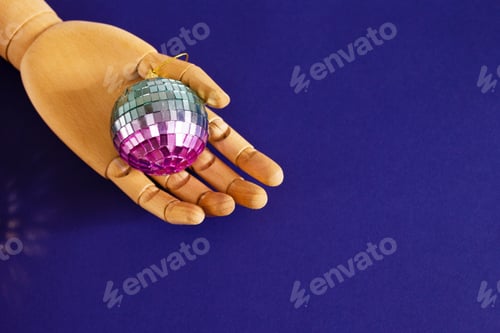Preview: Wooden Hand Holding Shiny Disco Ball on Blue Background. Retro Party, Celebration Concept.