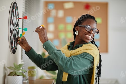 Preview: Smiling Woman Playing Darts In Office Setting