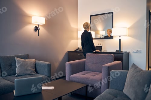 Preview: Beautiful woman looking in the mirror in hotel room