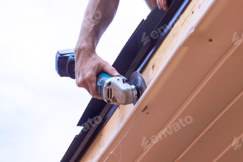 Preview: An employee cuts off vinyl soffit panels to given size on facade ceiling of a new home