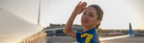 Preview: Portrait of cheerful air stewardess in blue uniform smiling at camera, posing outdoors at the sunset