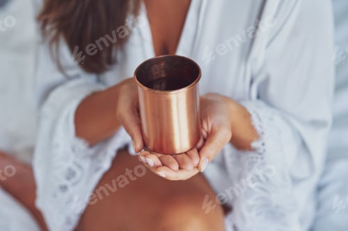 Preview: Nice looking brunette woman with copper cup of water