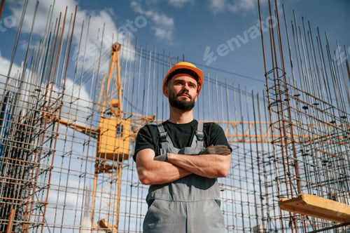 Preview: Standing against the crane with arms crossed. Man in uniform is working on the construction site