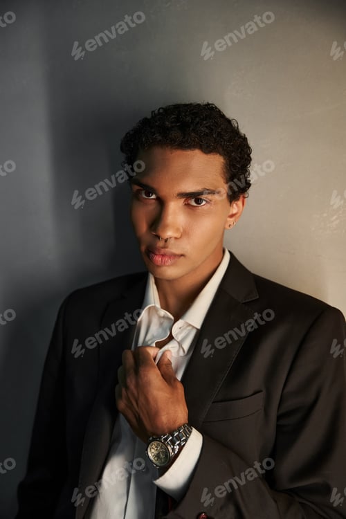 Preview: appealing young african american man in black elegant suit looking at camera on gray backdrop