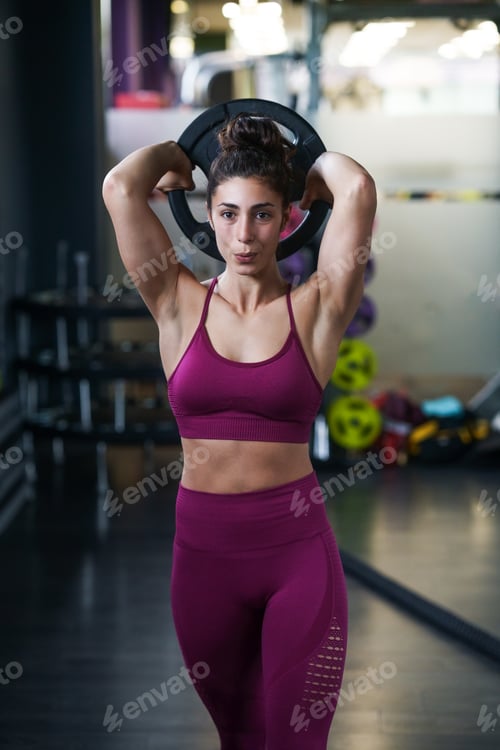 Preview: Athletic woman doing triceps push-ups with a barbell plate