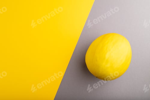 Preview: Ripe yellow melon on gray and yellow pastel background. Top view, copy space.