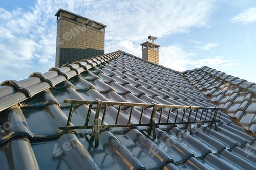 Preview: Closeup snow guard for safety in winter on house roof top covered with ceramic shingles