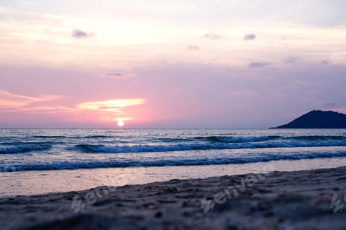 Preview: Colorful ocean beach sunset with deep orange blue sky and sun rays.