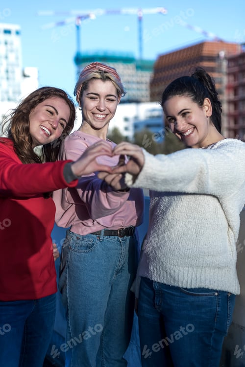 Preview: three female friends making heart shape from hand