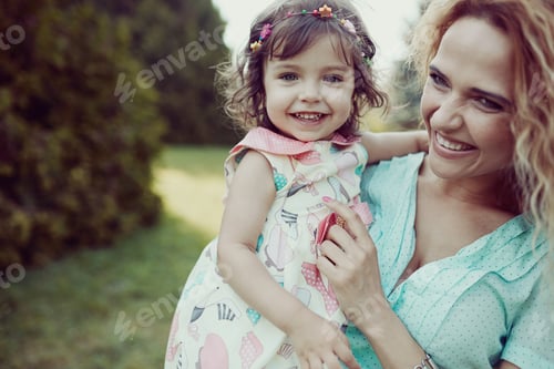 Preview: Happy mother and daughter laughing together outdoors