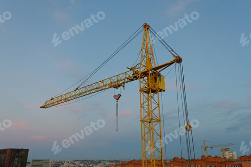 Preview: Yellow tower crane dominating the city skyline at sunset