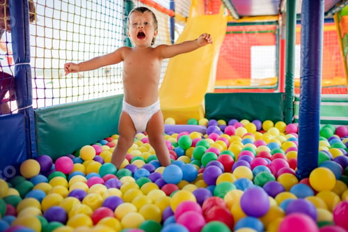 Vista previa: The kid plays in the playroom and rolls down the slide into the pool with small balls