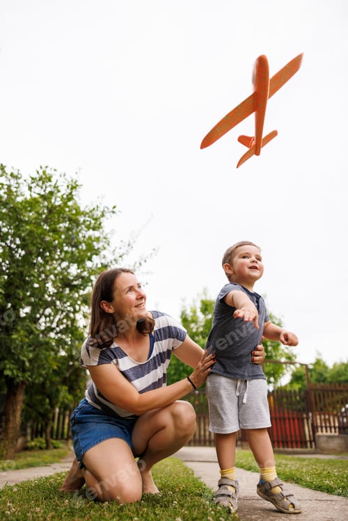 Preview: Mother and son having fun throwing toy planes while playing in the backyard