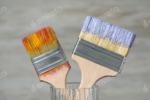 Preview: Brushes with color paints in glass on light background, closeup