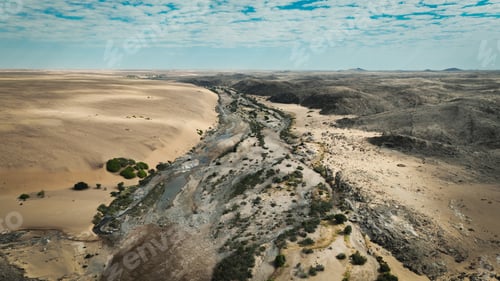 Preview: Aerial view of the wild landscape and river in the arid region of Angola under a cloudy sky