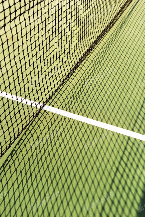 Preview: close up view of net with shadow on green tennis court