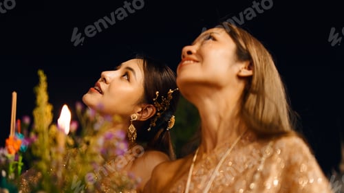 Preview: Thai women in traditional dress celebrating loi krathong festival at night