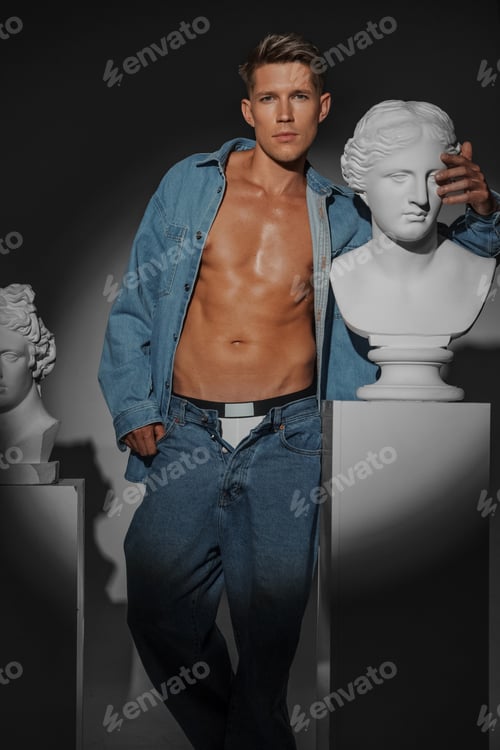Preview: Male dressed in denim shirt pose next to classical Greek bust sculpture