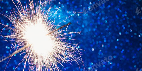 Preview: Bright sparkler on blue background. Celebrating New Year and Christmas.