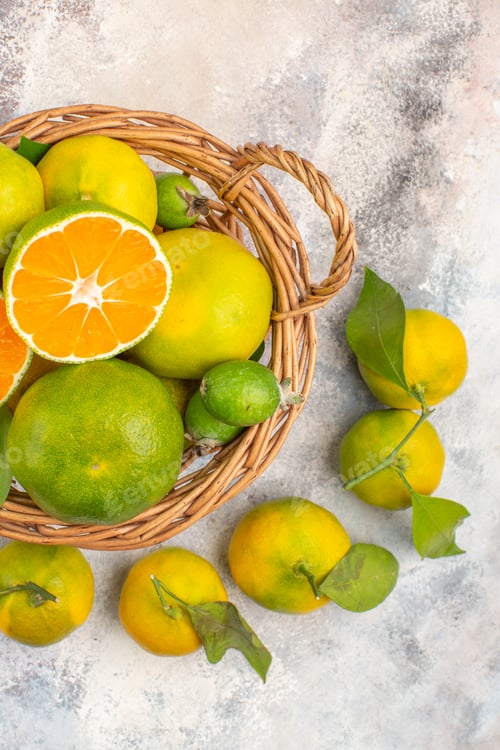 Preview: top view fresh mandarines in wicker basket surrounded by mandarines on nude background