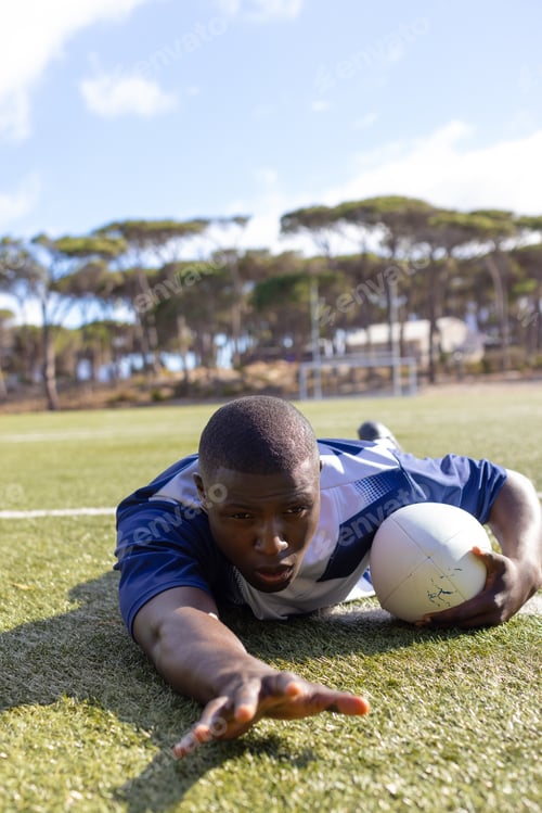 Preview: An African American young male rugby player scoring a try on a grass field