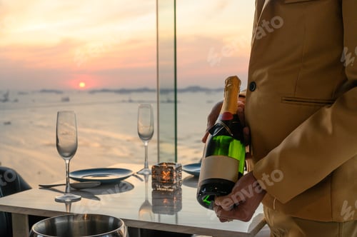 Preview: The waiter in uniform holding a bottle of green wine prepared to pour into a glass at restaurant