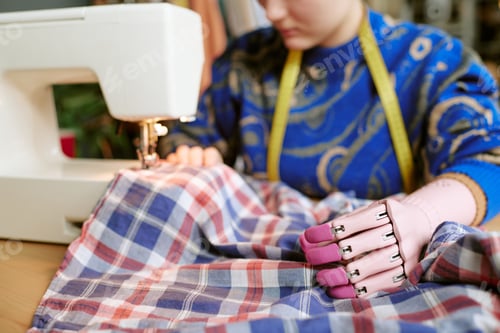 Preview: Young Caucasian Woman with Prosthetic Hand Sewing Second Hand Clothing
