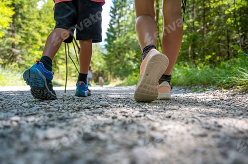 Preview: Mother and child walking and hiking on a footpath in green summer forest