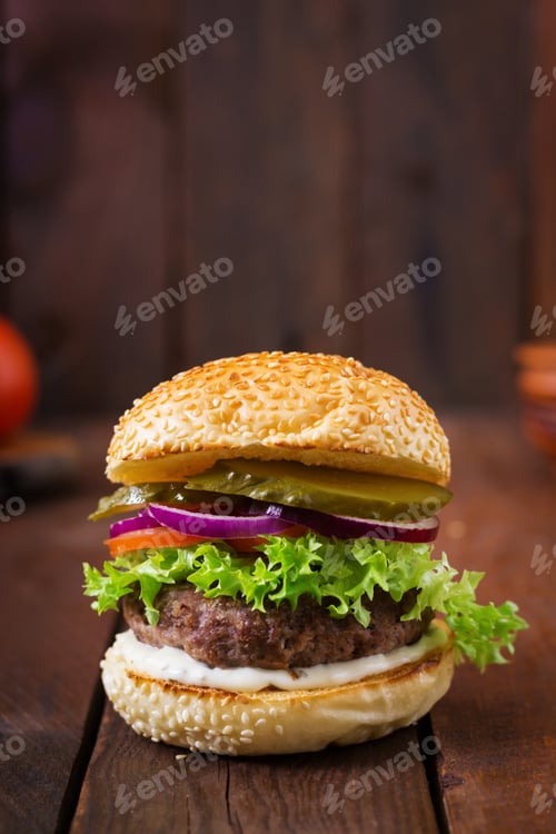 Preview: Big sandwich - hamburger burger with beef, pickles, tomato and tartar sauce on wooden background.