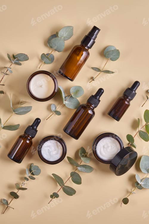 Preview: Set of beauty products in amber glass bottles and jars on beige background with eucalyptus leaves.