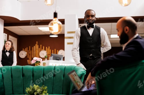 Preview: Bellboy assisting businessman in lobby