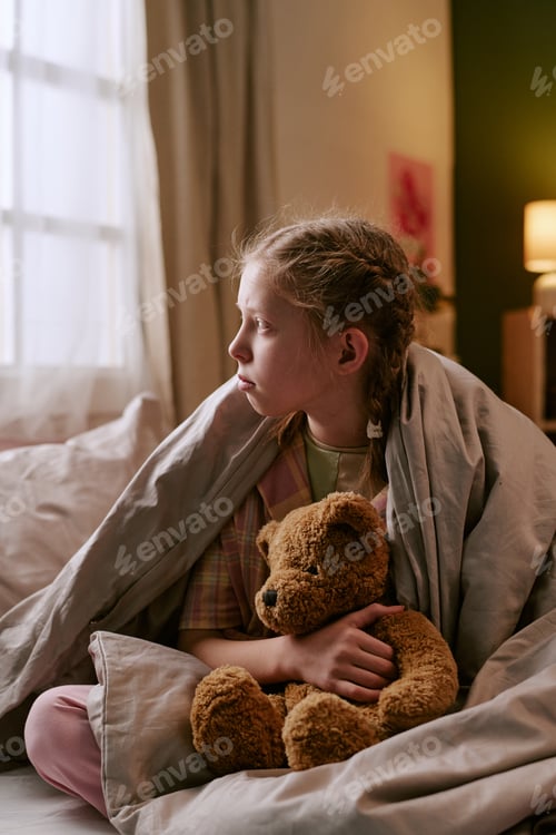 Preview: Girl Sitting on Bed Holding Toy Bear and Looking out Window