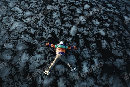 Preview: A Man In Ice Skates Lies On The Transparent Ice Of The Lake, View From Above, Aerial Photography