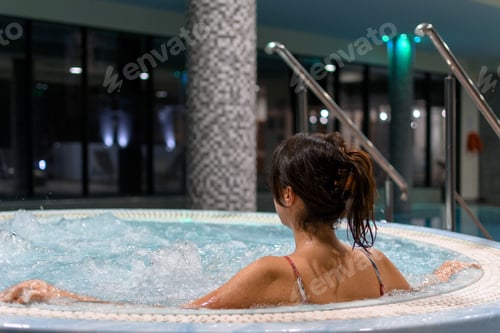 Preview: Rear view of woman in hot tub or whirlpool in spa