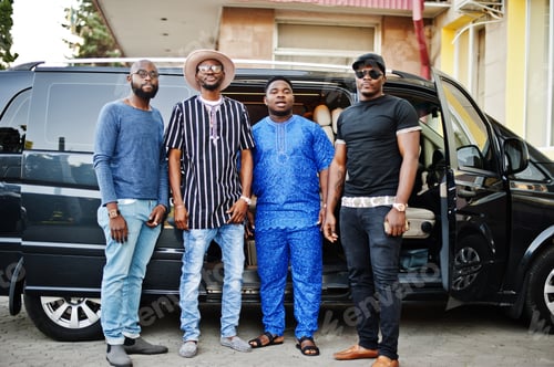 Preview: Black men wearing cool traditional clothes stand by the minivan.