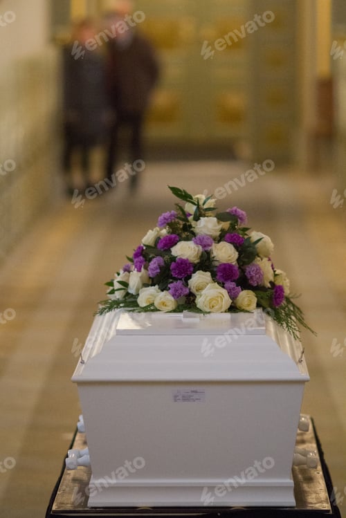 Preview: Vertical shot of a flower over a white casket with a blurred background