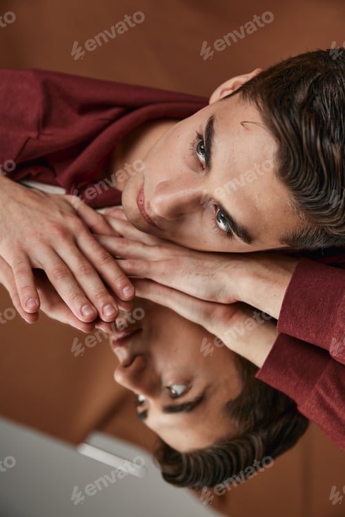 Preview: man in shirt lay down on glass and reflection portrait brown background