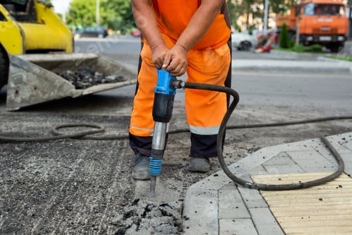 Preview: Road worker breaking street asphalt with jackhammer.