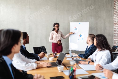 Preview: Businesswoman Pointing At Charts On Blackboard During Corporate Meeting Indoor
