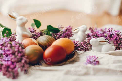 Preview: Modern colorful Easter eggs on rustic linen fabric and purple lilac flowers