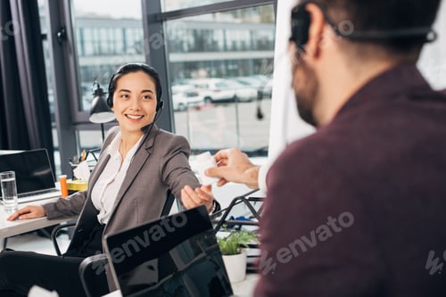 Preview: call center operator giving bottle with medicine to smiling coworker in office
