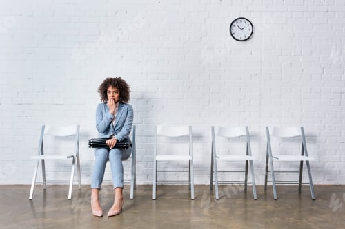 Preview: Scared businesswoman with briefcase sitting on chair and waiting