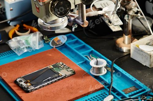 Preview: microscope over mobile phone near testing devices on table in repair workshop, maintenance business